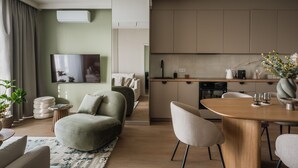 A modern living room with a sofa, a dining table with chairs, and a kitchen area with cabinets and appliances. - Electra Apartments by StayLab (Kraków)