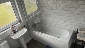 Ein modernes Badezimmer mit Badewanne, Waschbecken und Fenster.