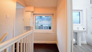 A narrow hallway with a window, a white sink, and a staircase. - House - Sleeps 4 - Parking - Pet Friendly (Ilkeston)