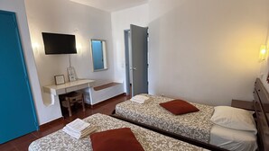 A hotel room with two beds, a desk, a TV, and a mirror.