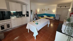 A compact living space with a kitchen, a dining area, and a seating area with two beds.