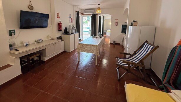 A spacious kitchen with a dining area, a TV mounted on the wall, and a refrigerator.