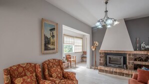 Una sala de estar con chimenea, dos sillones, un cuadro y una lámpara de pie.