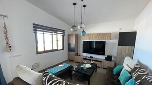 Een moderne woonkamer met een bank, salontafel en televisie.