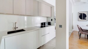 A modern kitchen with white cabinets, a stainless steel sink, and a coffee maker. - Beautiful Apartment - 2bd/4p - Arc de Triomphe (Paris)