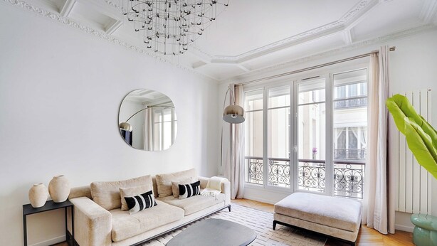 A living room with a sofa, a round mirror, a coffee table, and a view of a balcony. - Beautiful Apartment - 2bd/4p - Arc de Triomphe (Paris)