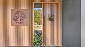 A wooden door with vertical slats, a tree relief, and a wreath. - Anglesea Summer Escape (Anglesea)