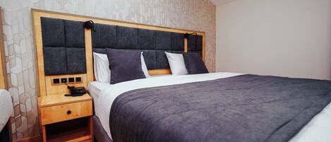 A modern bedroom with a large bed, a wooden nightstand, and a patterned wall.