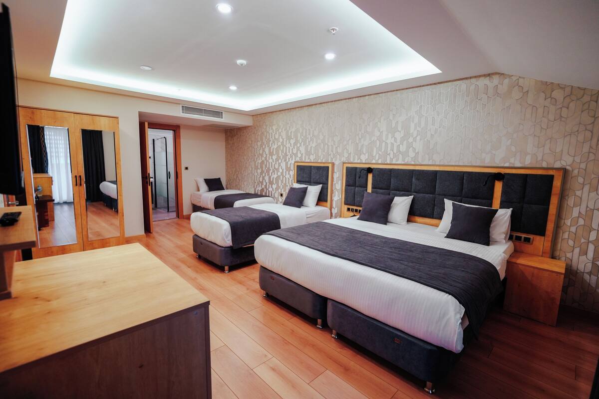 A modern hotel room with two beds, a wooden desk, and a large mirror.