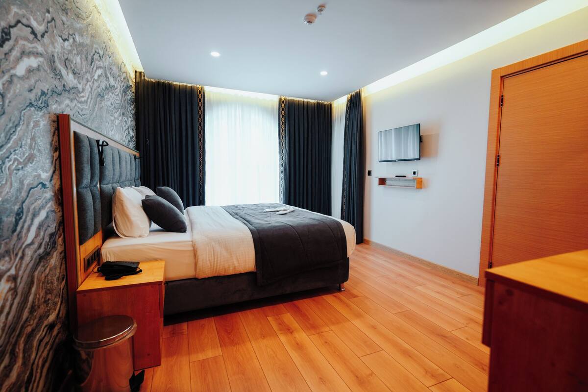 A modern bedroom with a bed, bedside table, and a TV mounted on the wall.