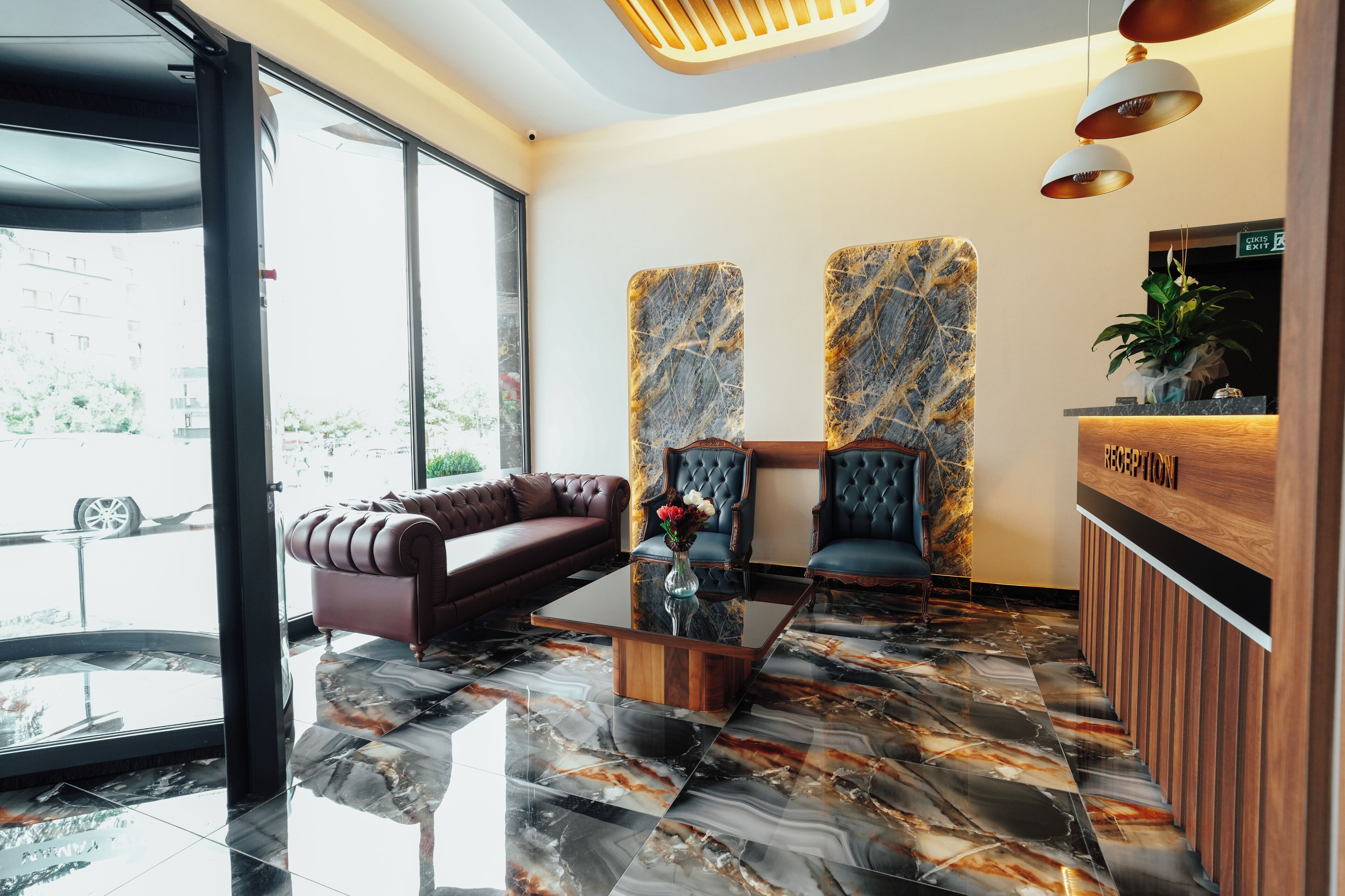 Una moderna área de recepción con piso de mármol, un sofá de cuero y dos sillones.