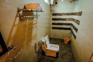 Un baño compacto con inodoro, secamanos, toallero y un pequeño cubo de basura.