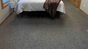Une chambre à coucher avec un lit, deux lampes fixées au mur, une fenêtre avec des rideaux et une porte.
