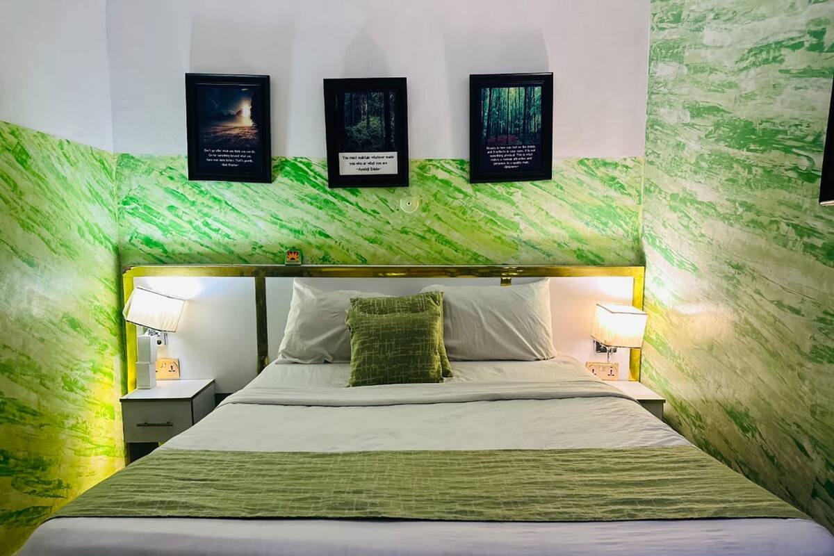 Une chambre d’hôtel avec un lit, deux lampes de chevet et trois citations encadrées accrochées au mur.