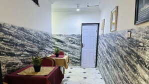A hallway with a dining area featuring tables and chairs, a door, and a textured wall. - The Autograph Basics Hotel (Lagos)