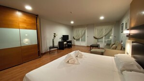 Een hotelkamer met een groot bed, een bureau, een stoel, een bank en een kledingkast.