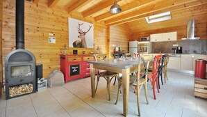 Un intérieur de chalet chaleureux, avec un revêtement en bois, une cheminée, un coin repas et une cuisine.