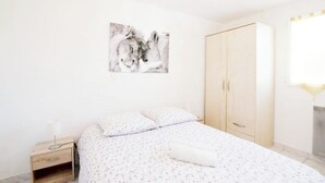 A bedroom with a bed, a nightstand, a wardrobe, and a wall-mounted picture.
