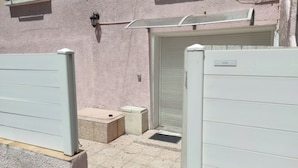 A gated entrance with a metal gate, a small concrete planter, and a closed garage door.