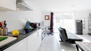 A modern kitchen with white cabinets, a black countertop, and a yellow squash on the counter.
