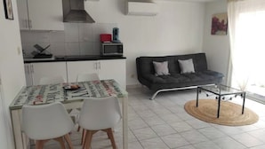 A compact living space with a kitchenette, dining area, and a sofa.