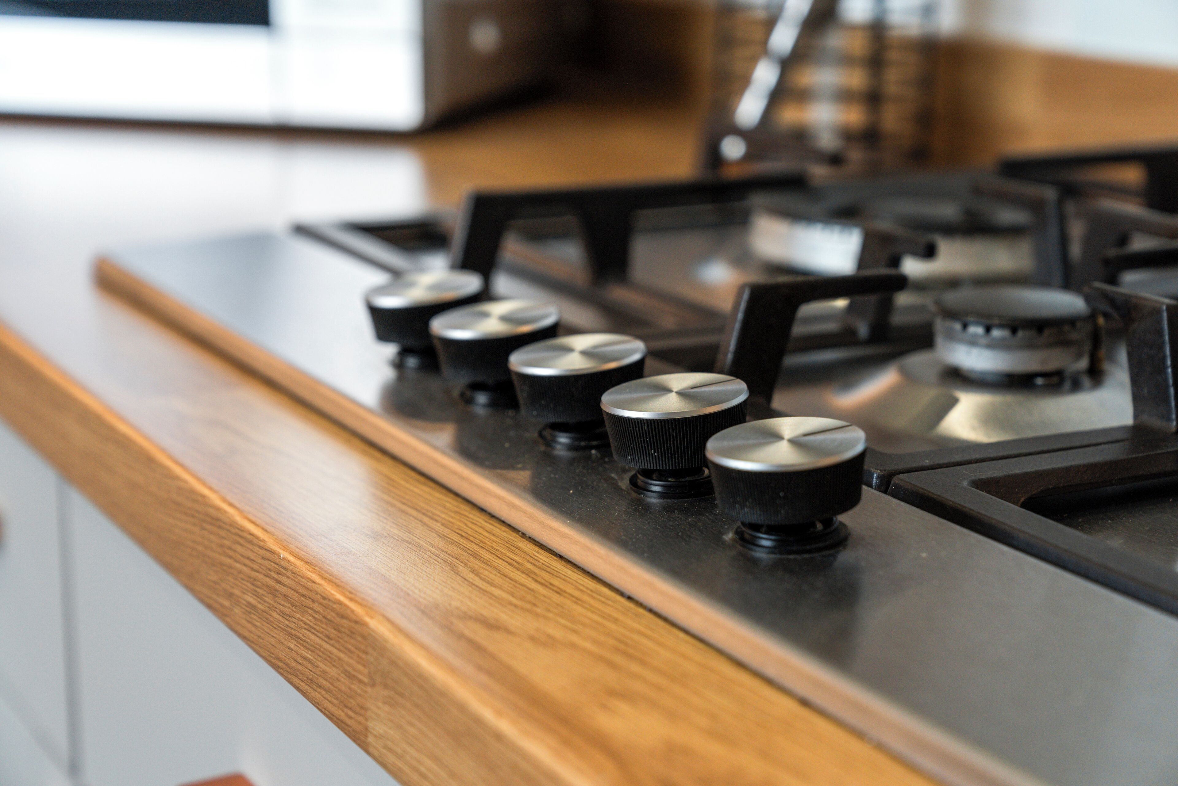 Une cuisine dotée d’un plan de travail en bois et d’une cuisinière à gaz avec des boutons noirs.