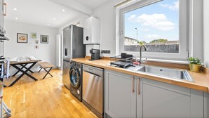 A modern kitchen with a washing machine, a coffee maker, and a sink. - Gateway to all of Scotland (Scone)