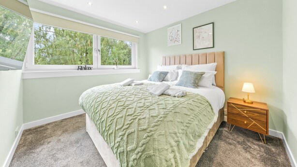 A bedroom with a large bed, a nightstand, a window, and artwork on the wall. - Gateway to all of Scotland (Scone)