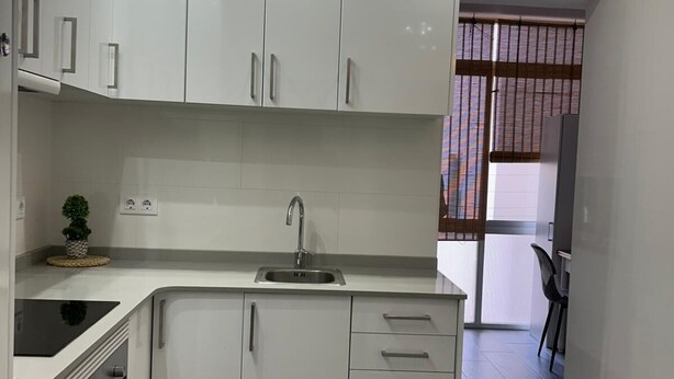 A modern kitchen with white cabinets, a stainless steel sink, and a black stovetop. - Holiday apartment Vinaròs beach vacations (Vinaròs)