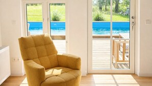 A mustard-colored armchair in a room with a view of a swimming pool through a sliding glass door. - Holiday Home 'Ferienhaus 'Huus Ant Diek Mit Pool'' with Private Pool, Private Terrace and Wi-Fi (Norden)