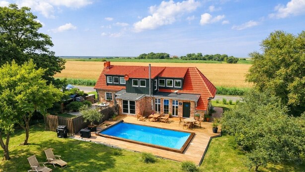 A two-story house with a swimming pool, surrounded by a fenced yard and trees. - Holiday Home 'Ferienhaus 'Huus Ant Diek Mit Pool'' with Private Pool, Private Terrace and Wi-Fi (Norden)