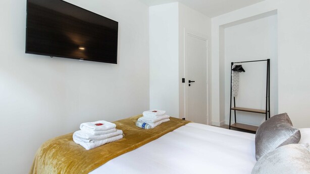 Une chambre d’hôtel équipée d’un lit, d’un téléviseur fixé au mur, d’une douche et d’un porte-serviettes.