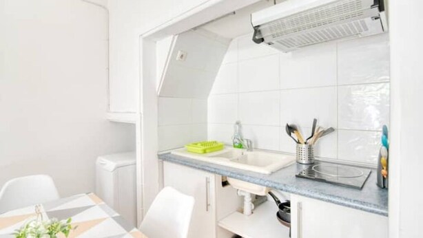 Una cocina moderna con armarios blancos, encimera gris y un lavabo integrado.