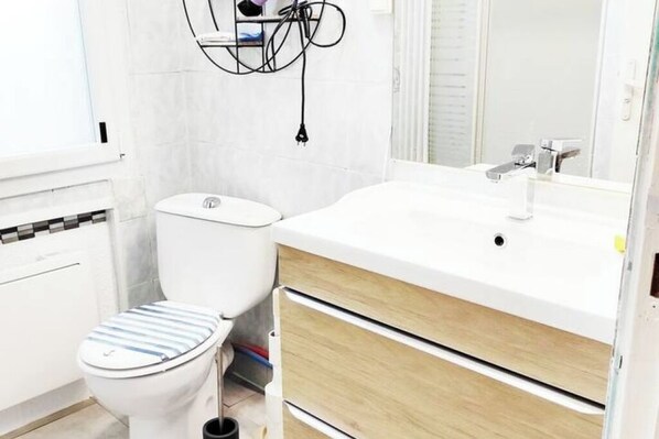 A small, clean bathroom with a toilet, a sink, and a mirror.