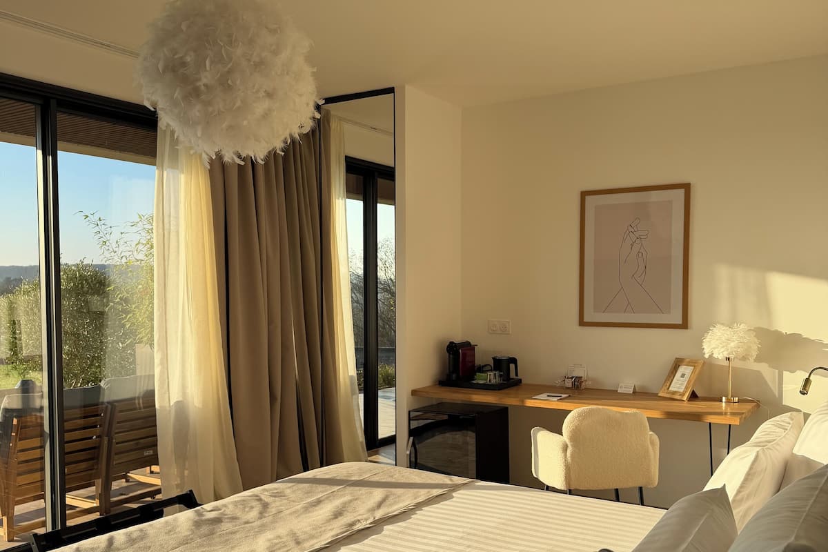 Une chambre d’hôtel avec un grand lit, un bureau, une chaise et une vue sur l’extérieur.