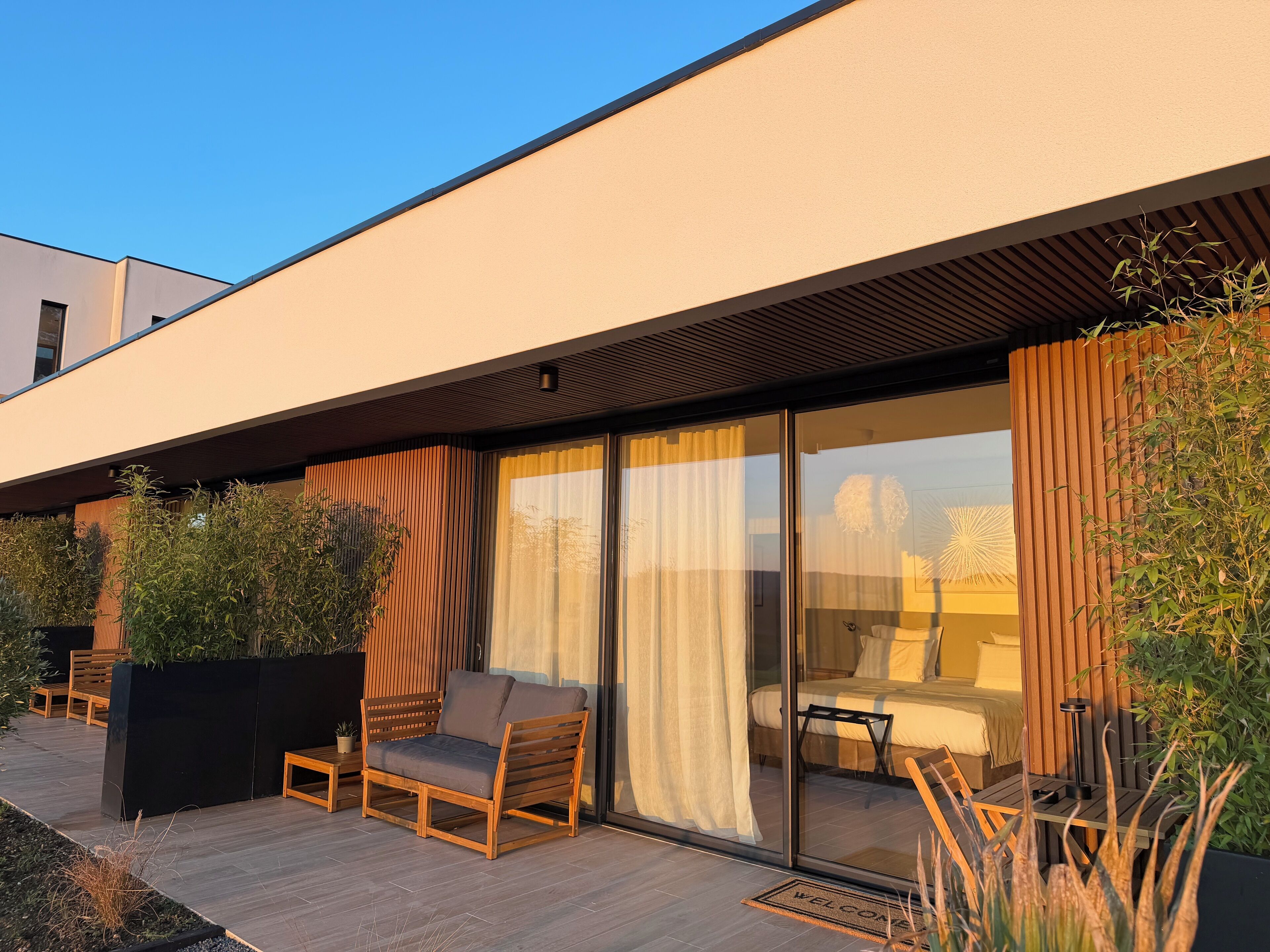 Un área de estar al aire libre moderna con sofá y sillones, un banco de madera y una mesita.