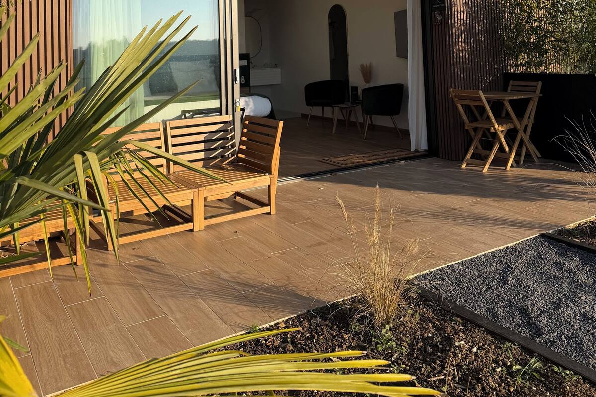 Une maison moderne dotée d’un patio aménagé avec des meubles en bois et offrant une vue sur l’intérieur.