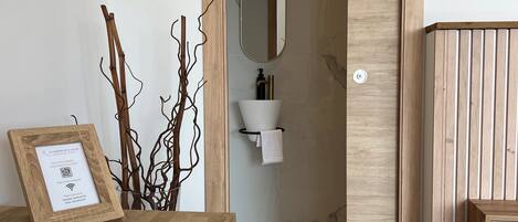 A room with a wooden desk, a framed certificate, a white chair, a mirror, and a wooden panel wall.