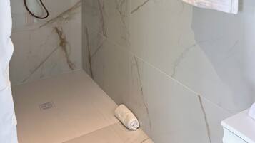 Une salle de bain moderne avec une douche, des murs en marbre et un porte-serviettes.