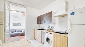 Cocina funcional con lavadora, refrigerador y armarios de madera.