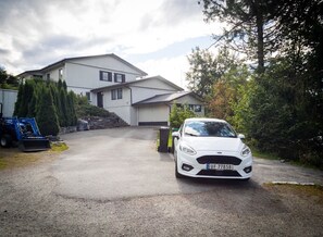 A white car parked in front of a two-story house with a driveway leading to the entrance. - Apartment with stunning fjord view near Ålesund (Møre og Romsdal)