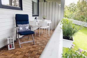 A wooden deck with a blue chair, white table, and potted plants. - Apartment with stunning fjord view near Ålesund (Møre og Romsdal)