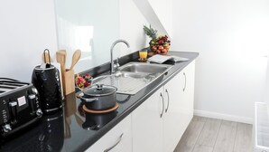 Una cucina moderna con mobili bianchi, un piano di lavoro nero e un lavello in acciaio inossidabile.