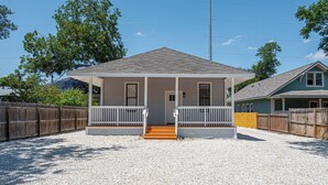 A single-story house with a covered porch, a gravel driveway, and a wooden fence. - Walk to Riverwalk! 3BR/2BA Gem Near Fun Downtown! (San Antonio)