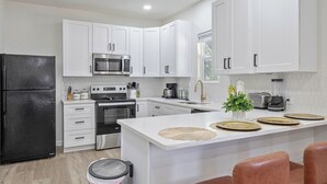 A modern kitchen with white cabinets, stainless steel appliances, and a central island with seating.