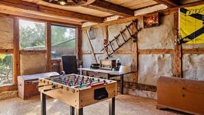Una habitación con mesa de fútbol, un escritorio con radio, una escalera y un armario de madera.