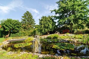 A tranquil garden with a pond, wooden bridge, and a red bench.