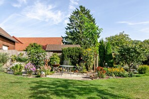 A garden with a wooden fence, a metal chair, and a variety of plants. - Holiday Apartment 'Gräfe' (Herzberg am Harz)