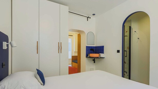 Une chambre à coucher avec un lit, une armoire, un miroir et une porte de salle de bain.