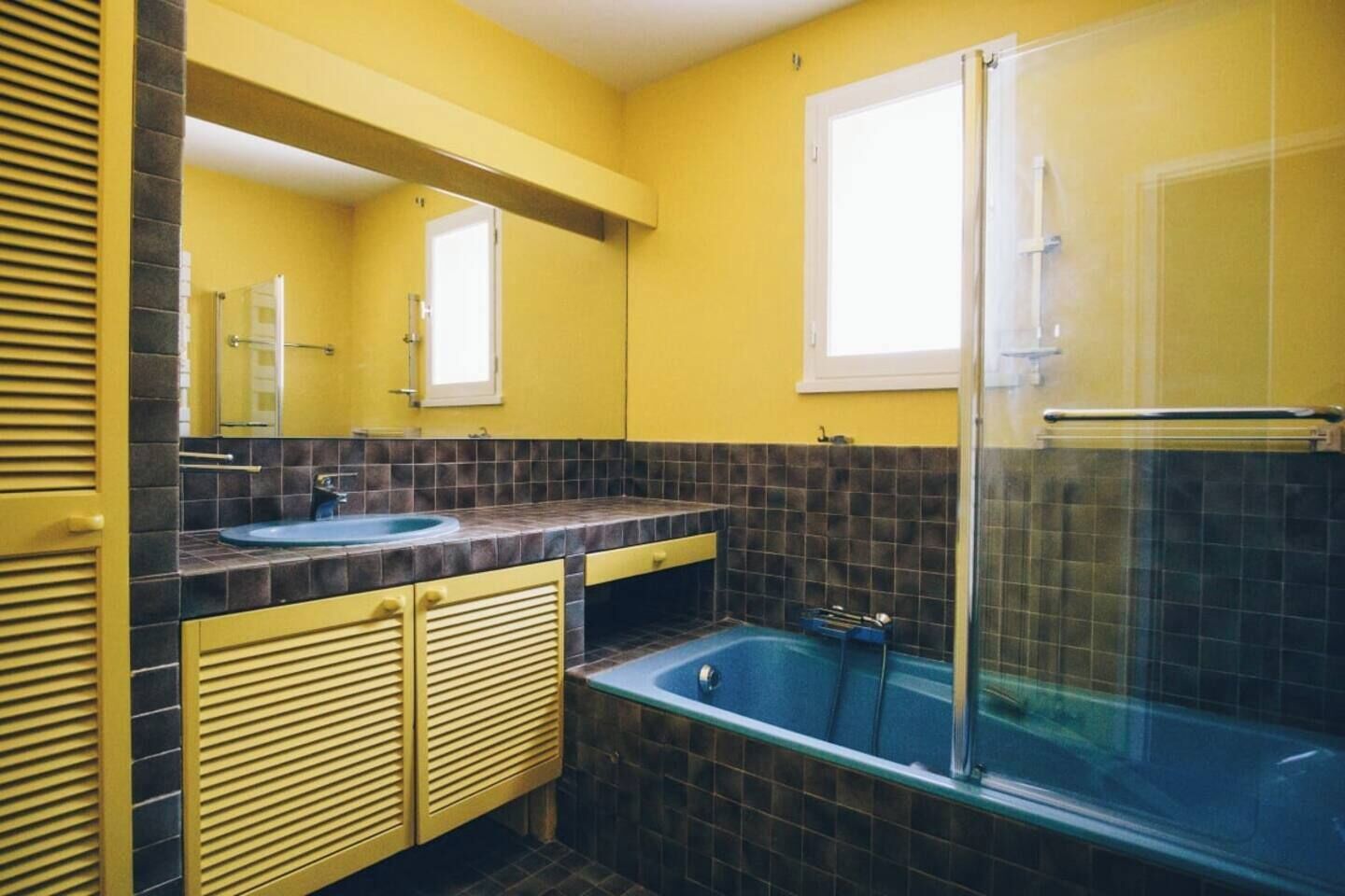 A bathroom with yellow walls, a sink, a bathtub, and a shower.